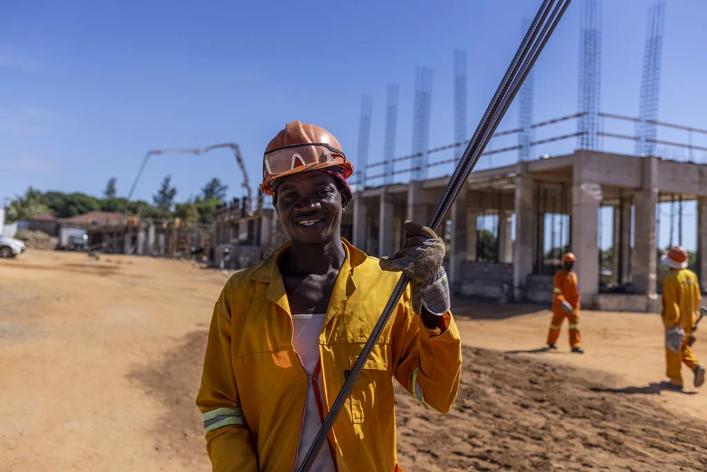 Ouvrier souriant en tenue orange et casque sur un chantier