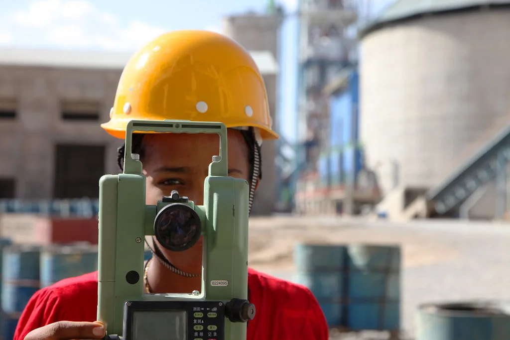 Technicien en casque jaune derrière une station topographique