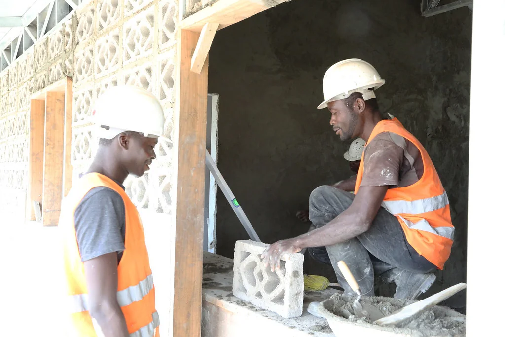 Maçons posant des claustras en béton dans un bâtiment